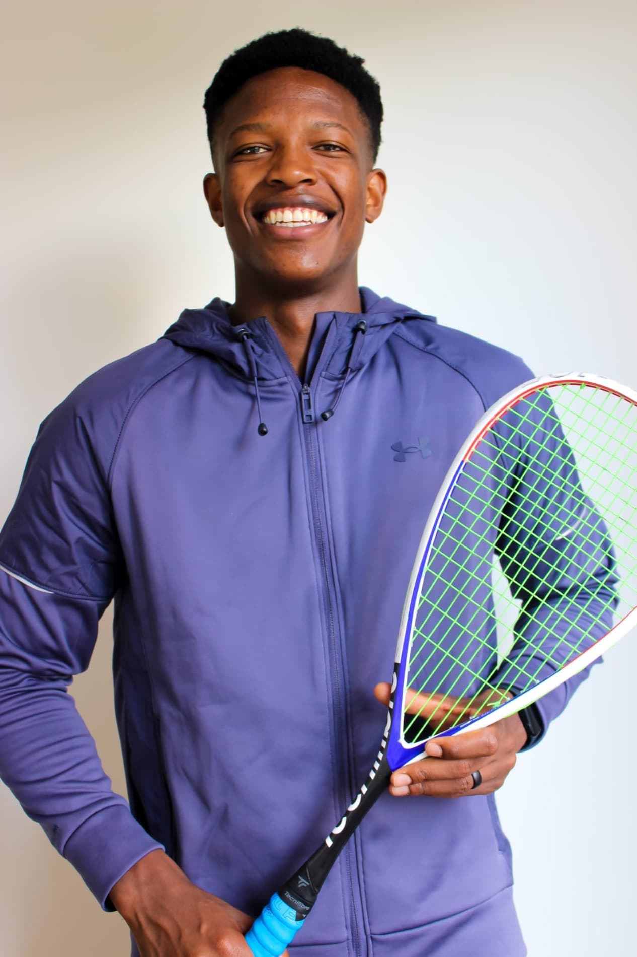 Head coach holding a squash racket in a portrait at the court