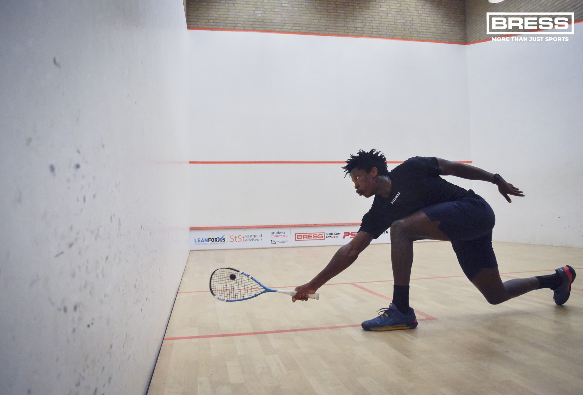 Elite squash player stretching to return a ball during an intense rally